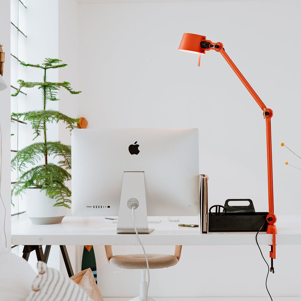Sfeerbeeld van de Tonone Bolt Desk 2 arm clamp bureaulamp in de kleur strekking orange.